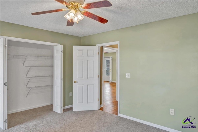 unfurnished bedroom featuring ceiling fan, a closet, light carpet, and a textured ceiling