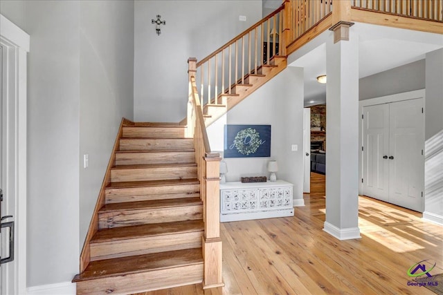 stairs featuring hardwood / wood-style flooring, a towering ceiling, and a fireplace