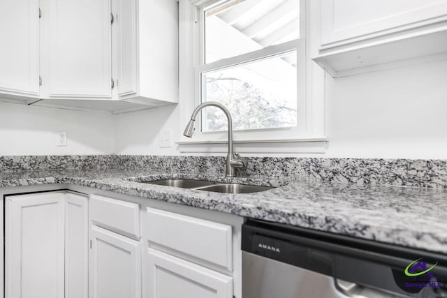 kitchen featuring light stone counters, stainless steel dishwasher, sink, and white cabinets