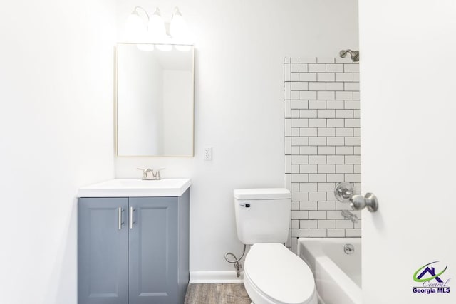 full bathroom with vanity, tiled shower / bath, wood-type flooring, and toilet