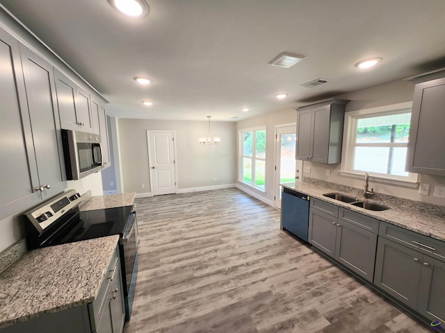 kitchen featuring light wood finished floors, appliances with stainless steel finishes, a sink, and a healthy amount of sunlight