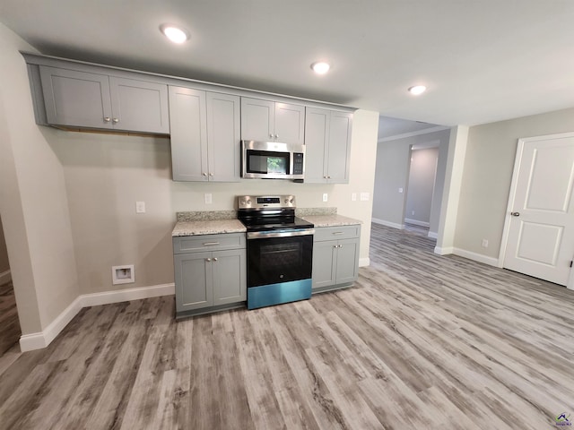 kitchen featuring light wood-style flooring, baseboards, stainless steel appliances, and gray cabinetry