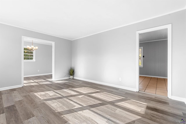 empty room featuring an inviting chandelier, wood-type flooring, and ornamental molding