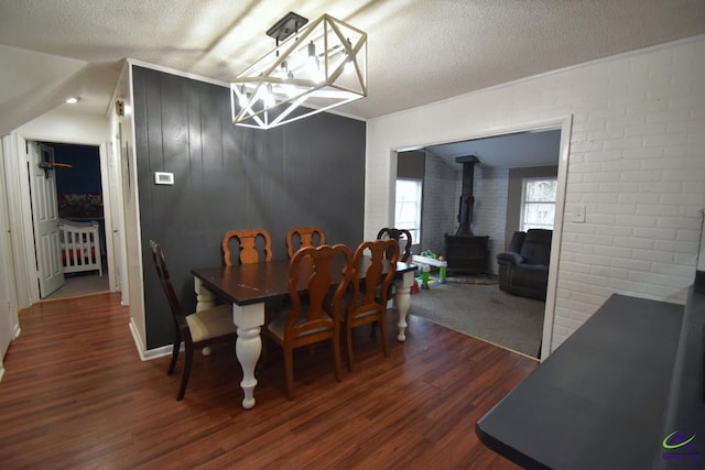 dining room with brick wall, dark hardwood / wood-style flooring, a textured ceiling, and a wood stove