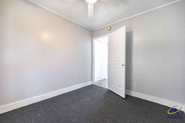 empty room with ornamental molding, ceiling fan, and dark carpet