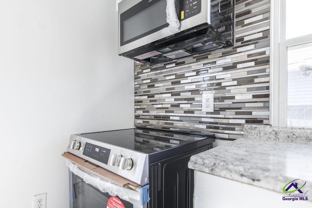 kitchen featuring light stone countertops, appliances with stainless steel finishes, and backsplash