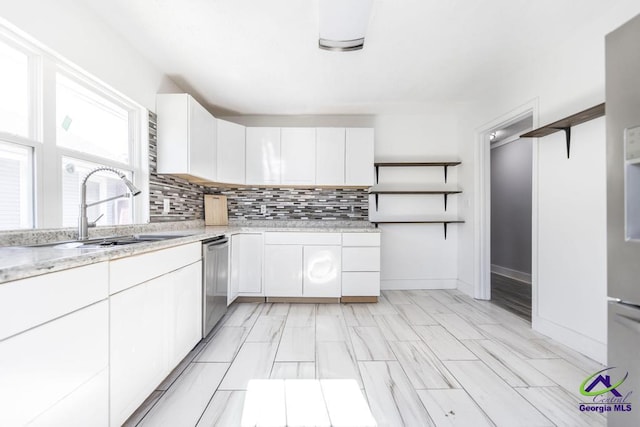 kitchen with tasteful backsplash, dishwasher, sink, and white cabinets