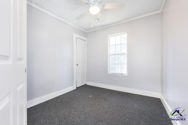 spare room with ornamental molding, ceiling fan, and dark colored carpet