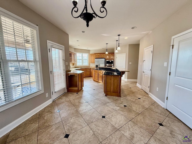 kitchen with a chandelier, a center island, hanging light fixtures, light tile patterned floors, and stainless steel appliances