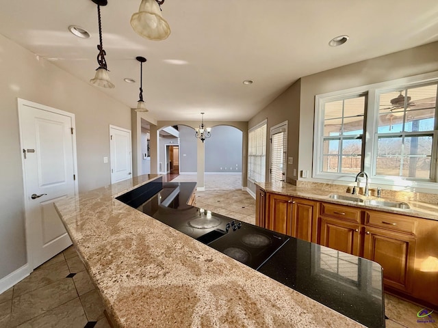 kitchen featuring sink, light stone counters, decorative light fixtures, a center island, and tile patterned flooring