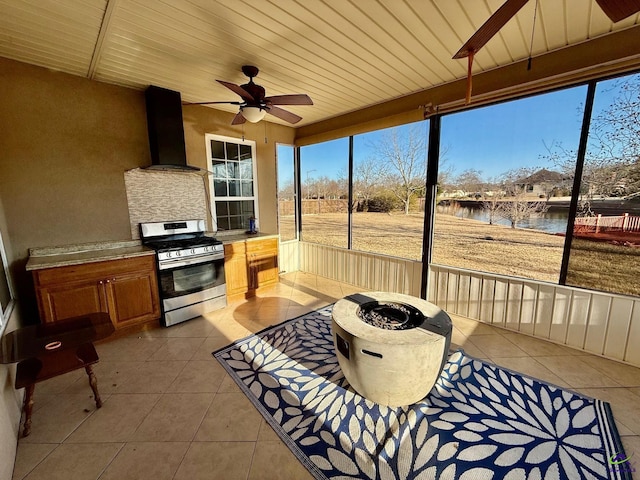 sunroom featuring ceiling fan, a water view, and wood ceiling