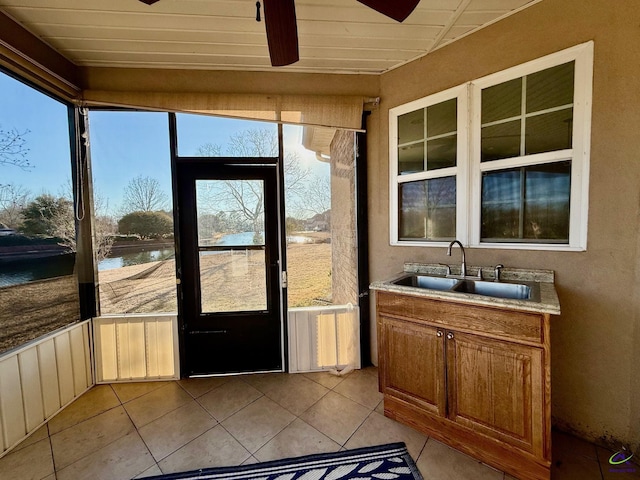 entryway with a water view, sink, light tile patterned floors, and ceiling fan