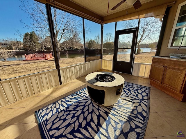 sunroom with a water view, sink, and ceiling fan