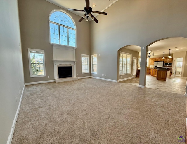 unfurnished living room featuring a high ceiling, plenty of natural light, and light carpet