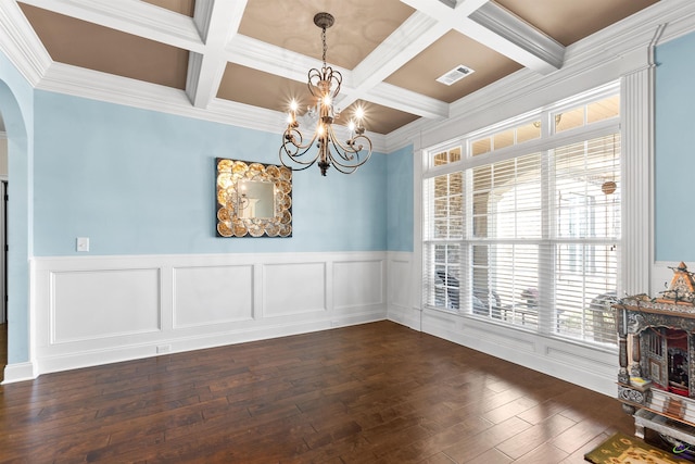 dining space with dark wood-type flooring, coffered ceiling, beamed ceiling, ornamental molding, and a chandelier