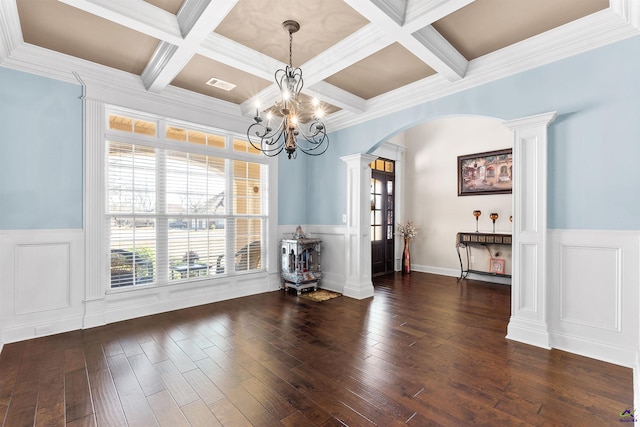 unfurnished dining area featuring dark hardwood / wood-style floors, decorative columns, beam ceiling, coffered ceiling, and an inviting chandelier