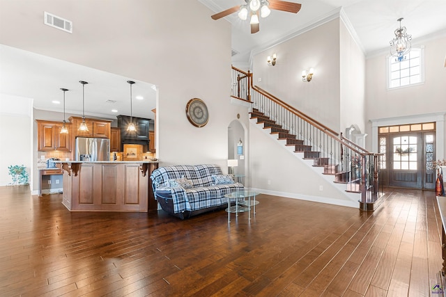 living room with dark hardwood / wood-style flooring, a towering ceiling, ornamental molding, and ceiling fan