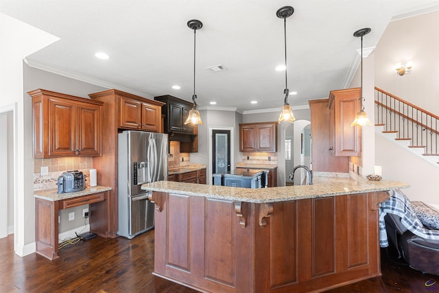 kitchen featuring stainless steel fridge, light stone countertops, dark hardwood / wood-style flooring, decorative light fixtures, and kitchen peninsula