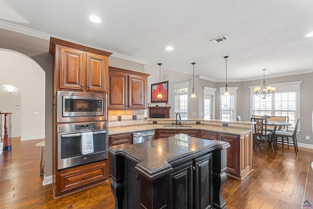 kitchen featuring sink, stainless steel appliances, a center island, decorative light fixtures, and kitchen peninsula