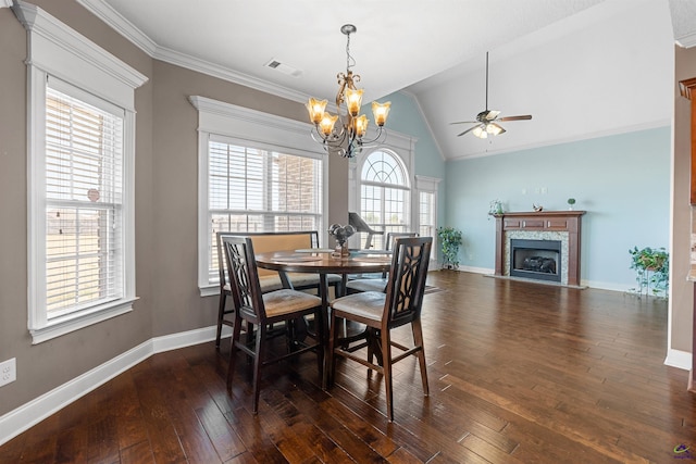 dining space featuring dark hardwood / wood-style floors, ceiling fan with notable chandelier, lofted ceiling, ornamental molding, and a high end fireplace