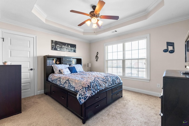 carpeted bedroom with crown molding, a tray ceiling, and ceiling fan