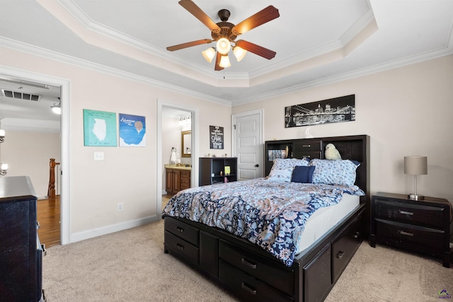 bedroom featuring connected bathroom, ornamental molding, light colored carpet, ceiling fan, and a tray ceiling