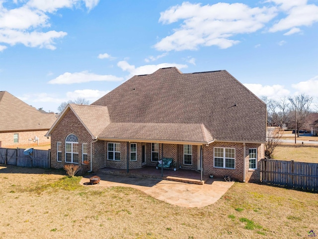 rear view of property featuring a fire pit, a lawn, and a patio