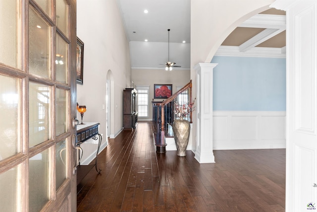 foyer featuring a towering ceiling, ceiling fan, dark hardwood / wood-style flooring, and ornate columns