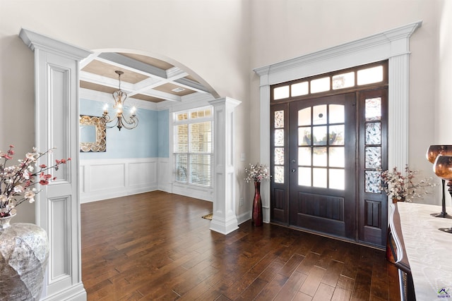 foyer entrance featuring coffered ceiling, an inviting chandelier, dark hardwood / wood-style flooring, beam ceiling, and decorative columns