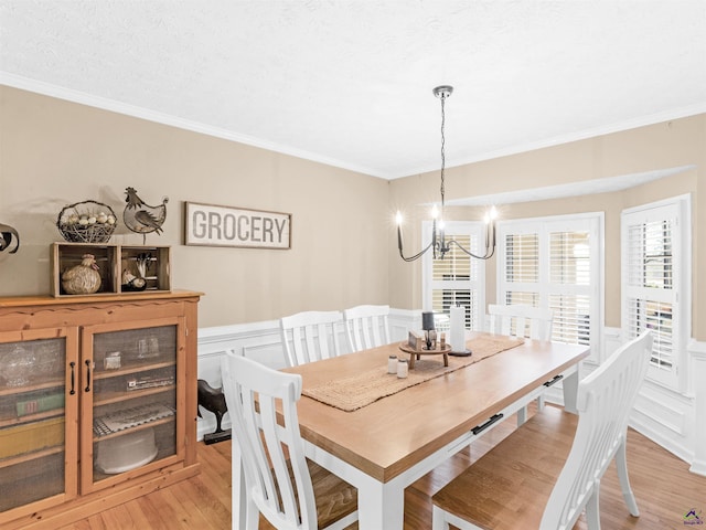 dining room with ornamental molding, a chandelier, a textured ceiling, and light hardwood / wood-style floors