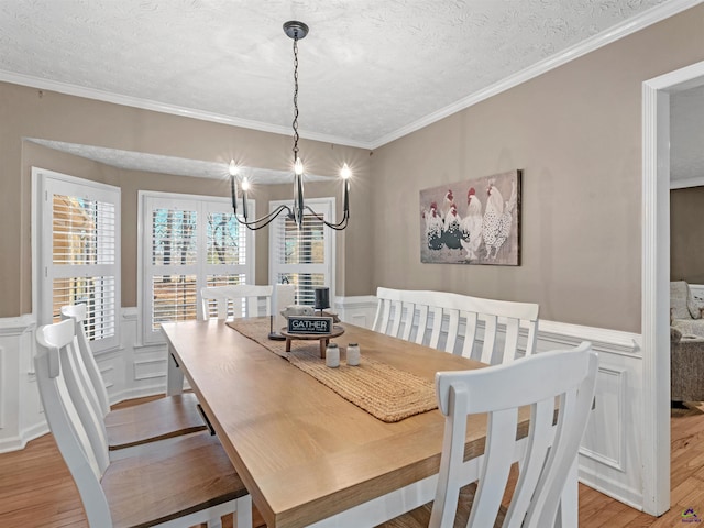 dining room with ornamental molding, a chandelier, light hardwood / wood-style floors, and a textured ceiling