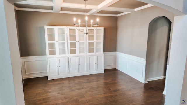 unfurnished dining area with coffered ceiling, crown molding, an inviting chandelier, dark hardwood / wood-style flooring, and beamed ceiling