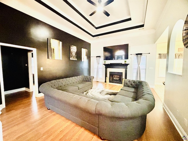 living room featuring a raised ceiling, hardwood / wood-style floors, and ceiling fan