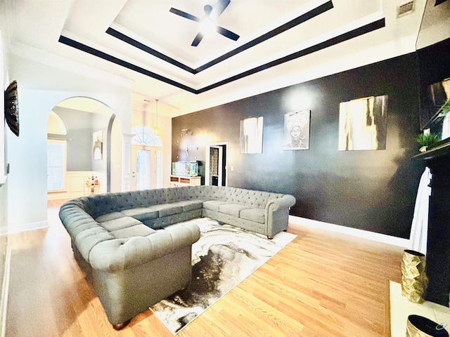 living room featuring ceiling fan, wood-type flooring, and a raised ceiling