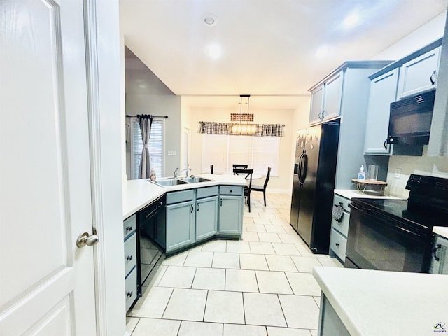 kitchen with light tile patterned floors, sink, hanging light fixtures, black appliances, and blue cabinets