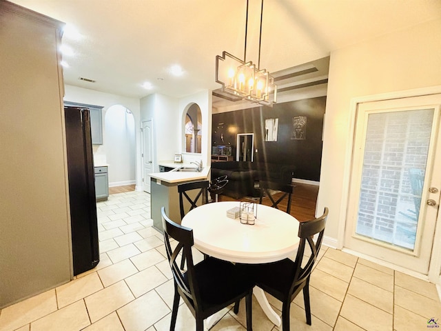 dining space with light tile patterned flooring, sink, and a chandelier