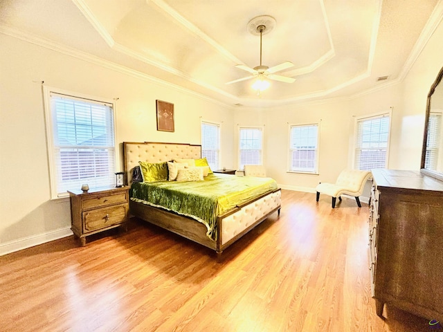 bedroom with a raised ceiling, hardwood / wood-style flooring, and multiple windows