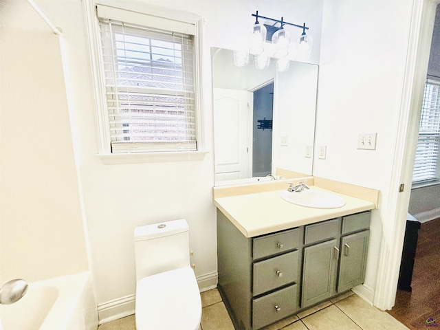 bathroom featuring vanity, a healthy amount of sunlight, tile patterned floors, and toilet