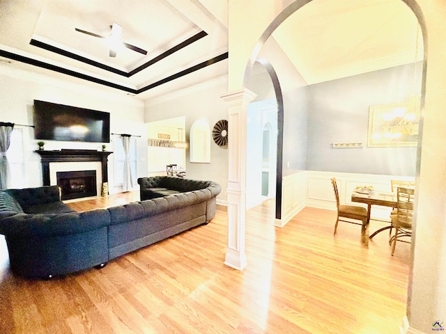 living room featuring ornate columns, crown molding, hardwood / wood-style floors, and a tray ceiling