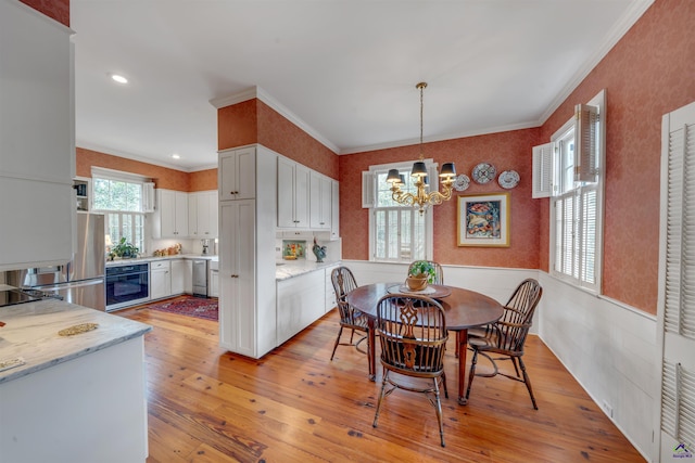 dining room with crown molding, light hardwood / wood-style floors, and a notable chandelier