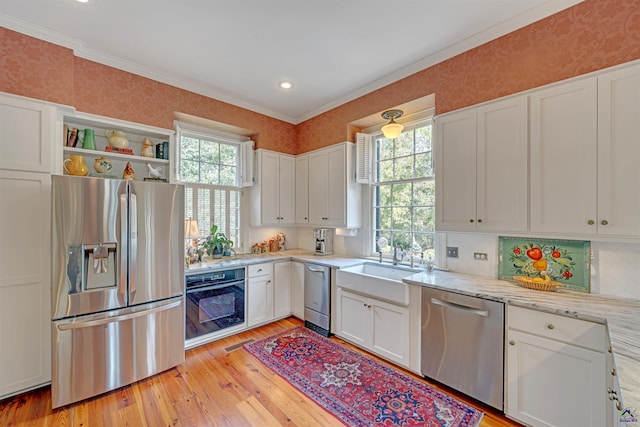 kitchen with white cabinetry, sink, stainless steel appliances, light stone countertops, and light hardwood / wood-style flooring