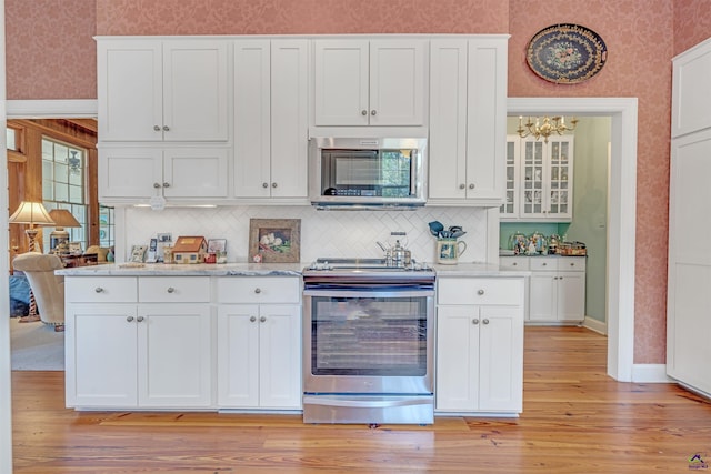 kitchen with white cabinetry, decorative backsplash, stainless steel appliances, and light hardwood / wood-style floors