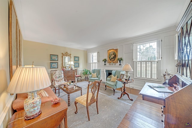 living area featuring light hardwood / wood-style flooring, crown molding, and a fireplace