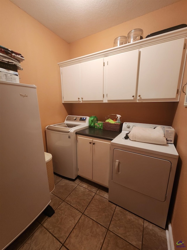 clothes washing area with dark tile patterned flooring and cabinets