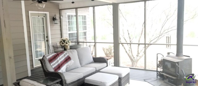 sunroom featuring ceiling fan and a wood stove