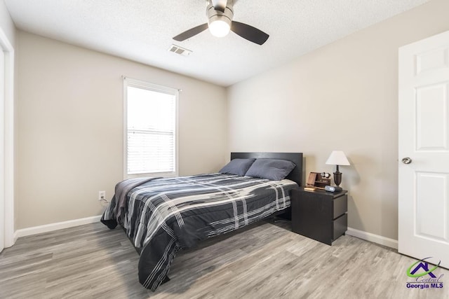 bedroom with ceiling fan, a textured ceiling, and light wood-type flooring