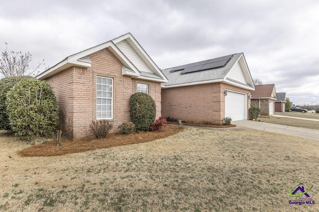 view of front of house featuring a garage, a front yard, and solar panels