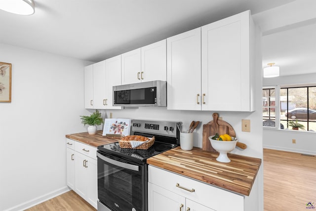 kitchen featuring wood counters, appliances with stainless steel finishes, light hardwood / wood-style flooring, and white cabinets