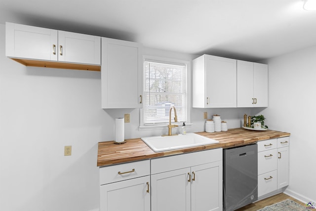 kitchen featuring wood counters, dishwashing machine, sink, and white cabinets