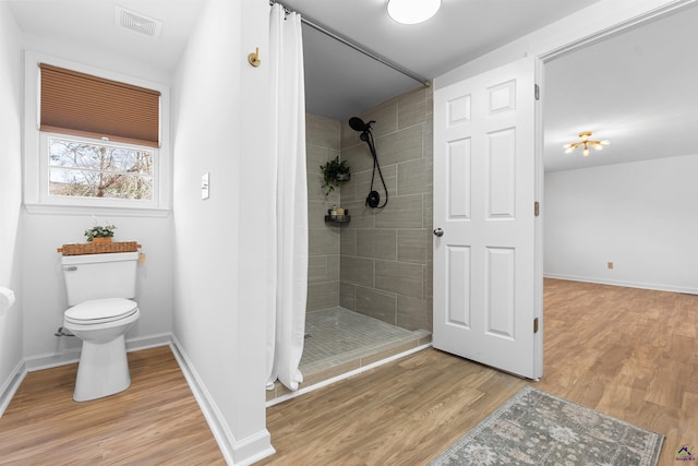 bathroom with a shower with curtain, wood-type flooring, and toilet